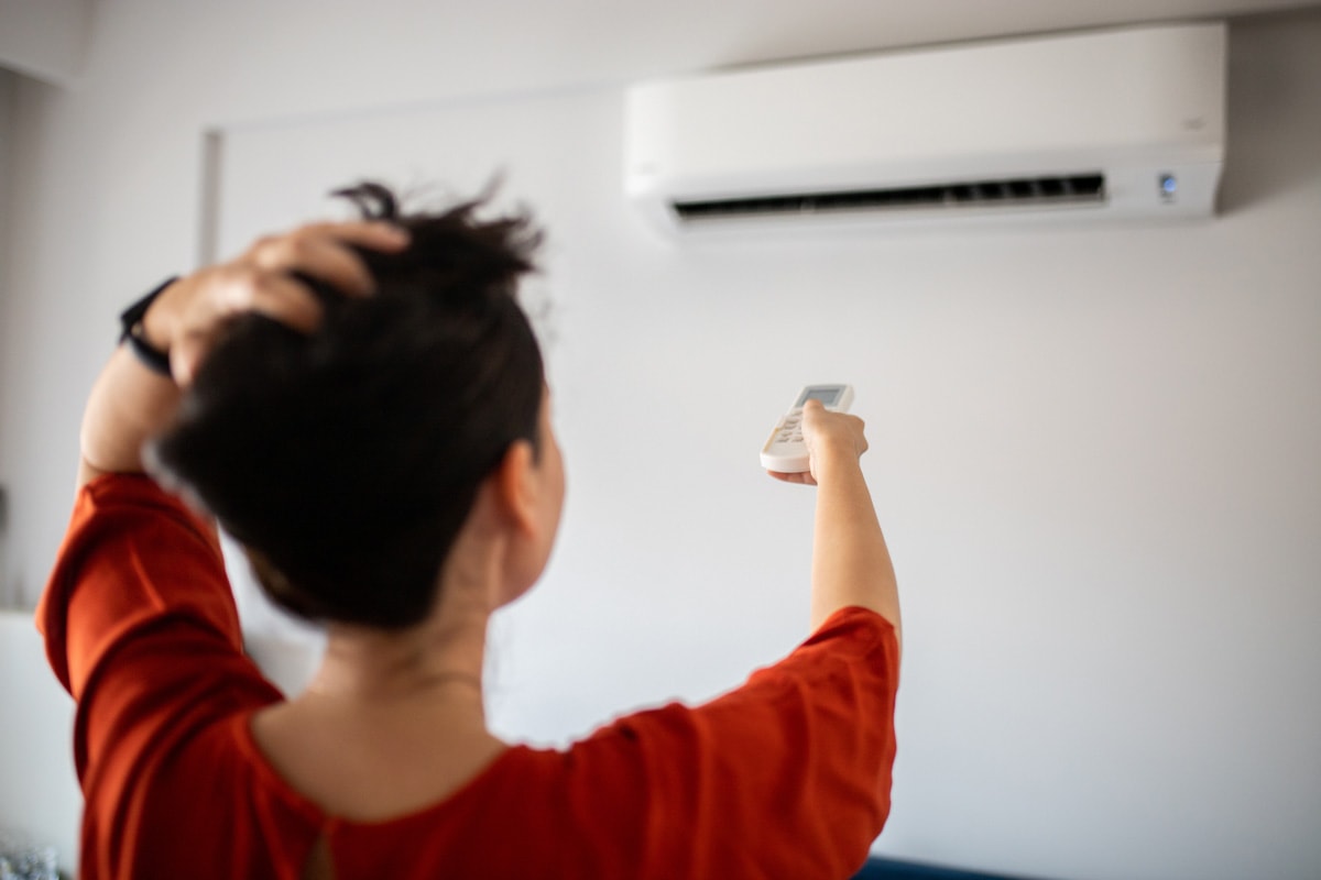 Woman switching on air conditioner