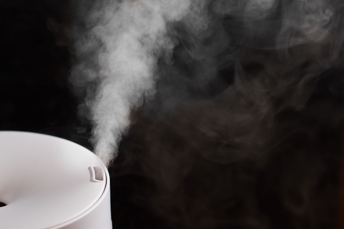 close up photo of a top view air humidifier vapor blowing black background