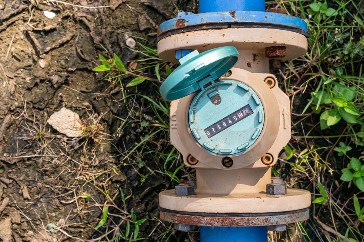 close up photo of a water meter on the ground soil of back lawn