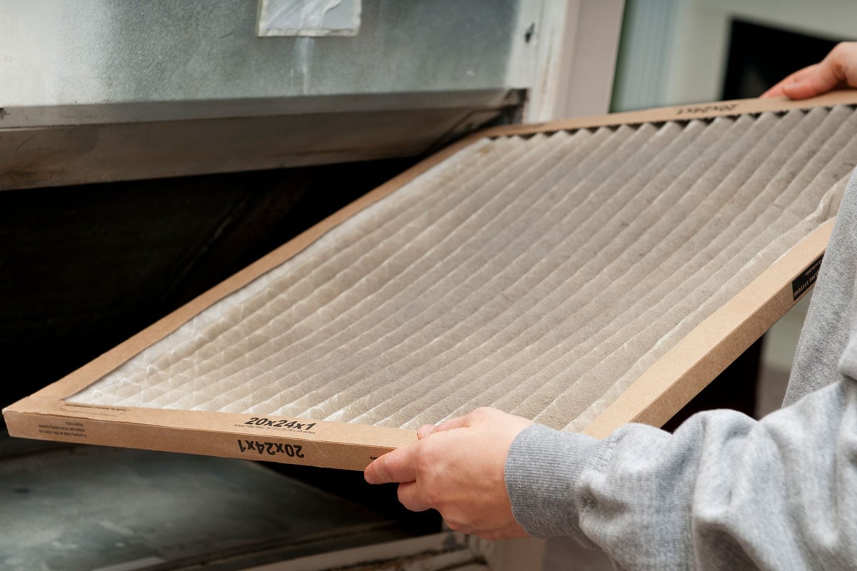 Man holding furnace air filter for cleaning