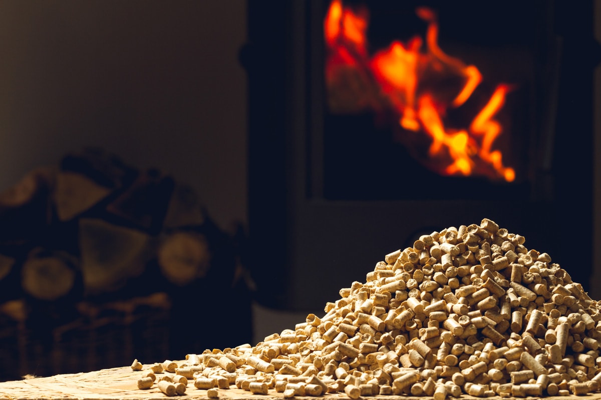 wooden pellets lie on a table in front of a fireplace with burning firewood