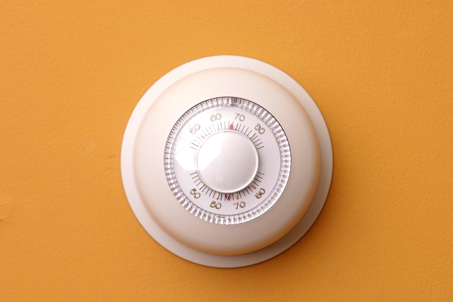 A closeup of a thermostat on a orange wall set to 68 degrees stock 