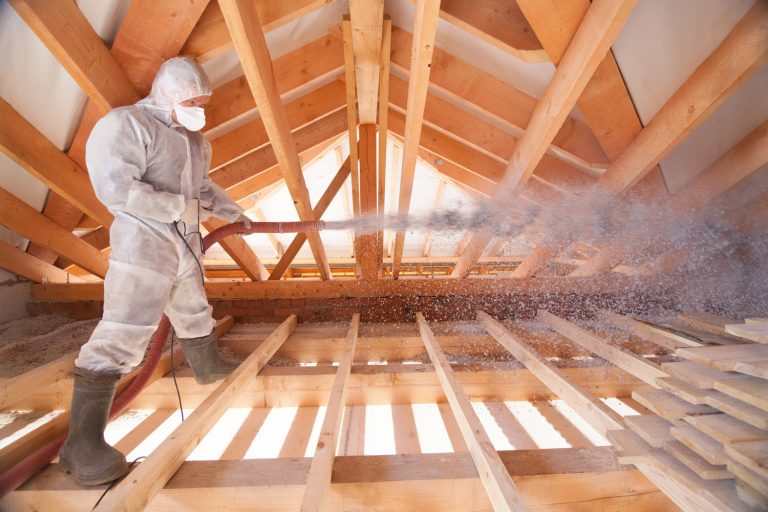 A man is spraying ecowool insulation in the attic of a house. Insulation of the attic or floor in the house - Is Blown In Insulation Flammable [Can It Catch Fire]