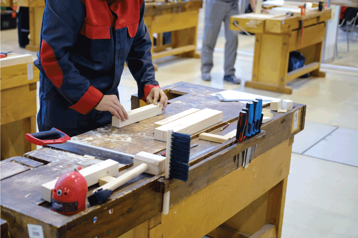 A man puts a piece of wood on a workbench for carpentry