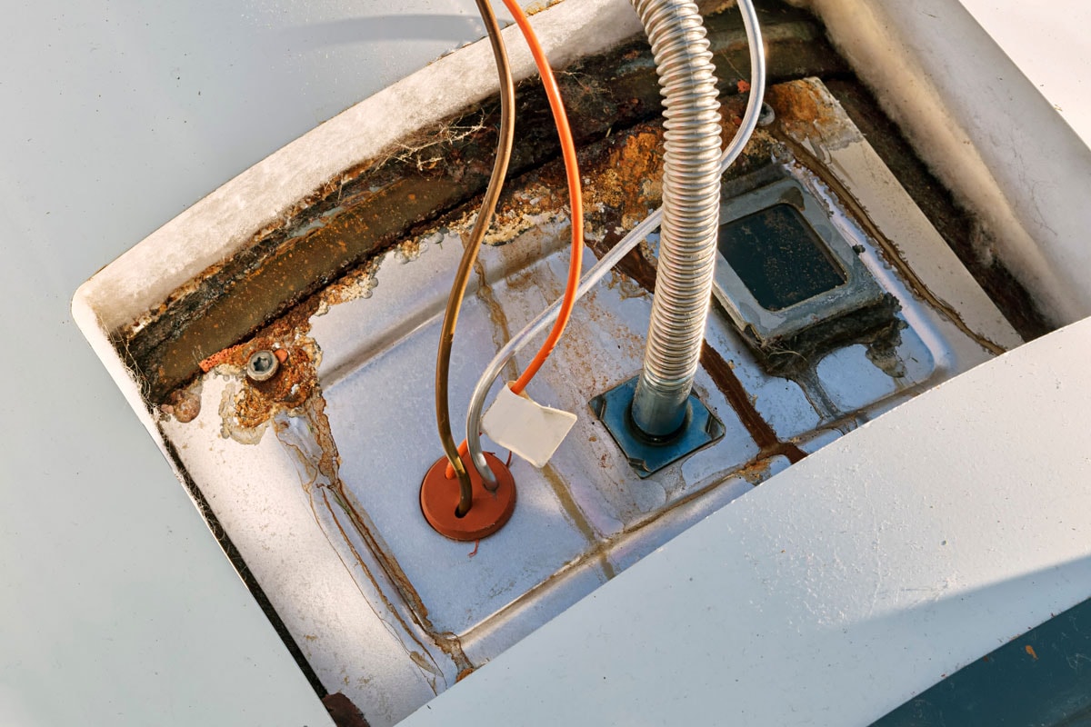 A side panel of a damaged water heater shows the rust and water damage rendering it unusable