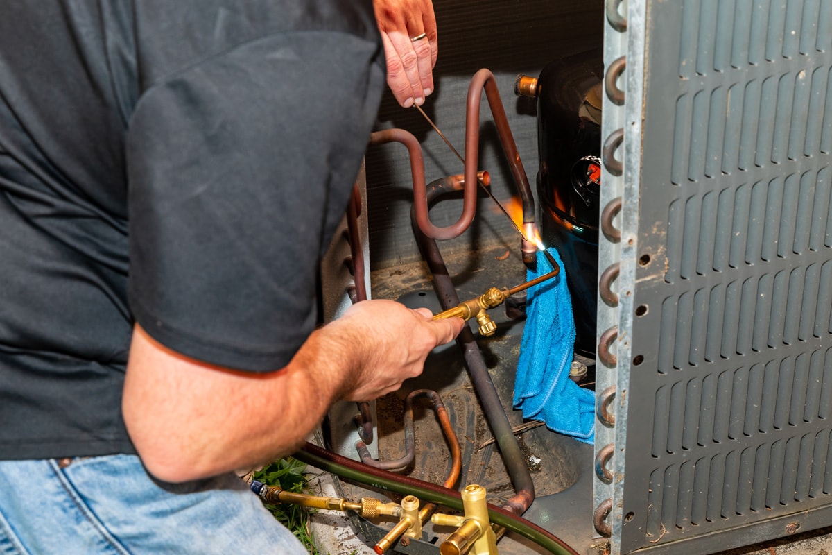 Air Conditioner Technician using a brazing torch to repair equipment