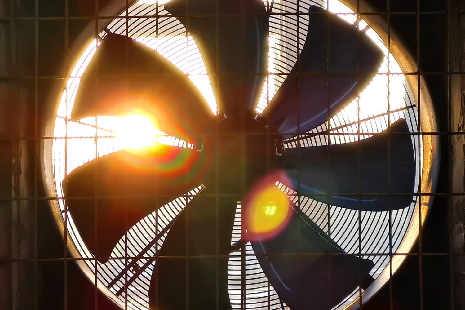 Close-up of big industrial fan in a factory. Ventilation of plant building. Backlit, sun light, rays of light.
