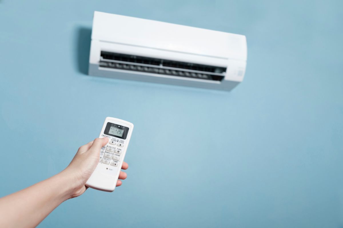 Close-up of men hand operating air conditioner with remote control