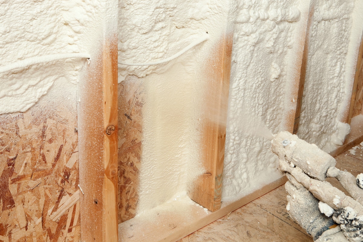 Construction Worker Spraying Expandable Foam Insulation between Wall Studs