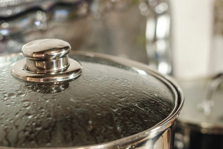 Cooking metal pot with lid covered with condensate water drops is on the stove. Kitchen background close up. Boiling water concept - Can Condensation In My Home Ruin Electronics