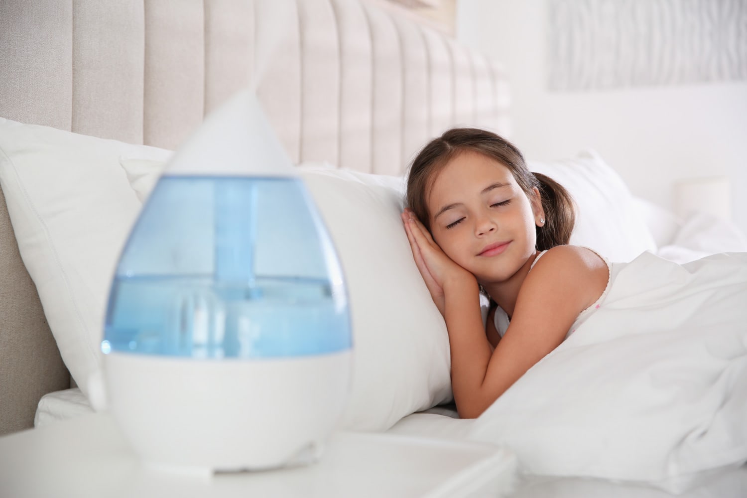 Cute little girl sleeping in bedroom with modern air humidifier