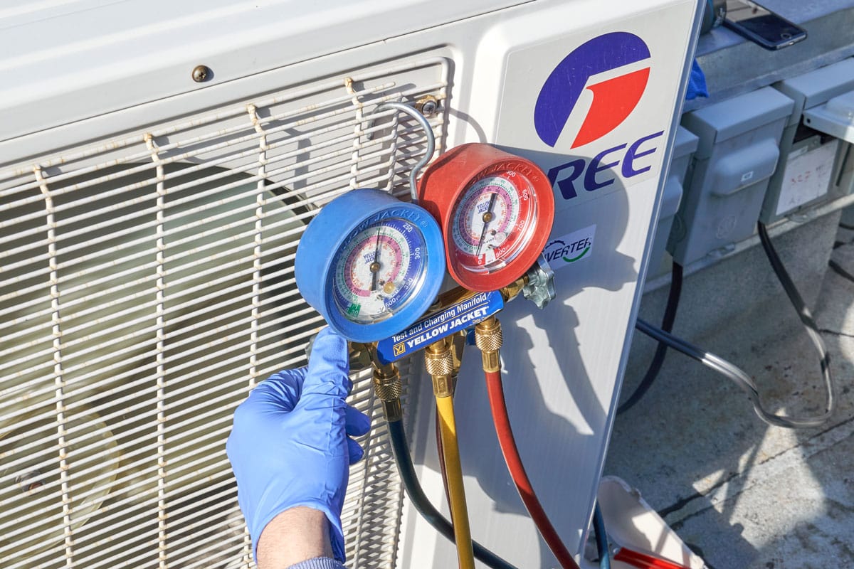 Engineer checking AC refrigerant level and refilling freon.