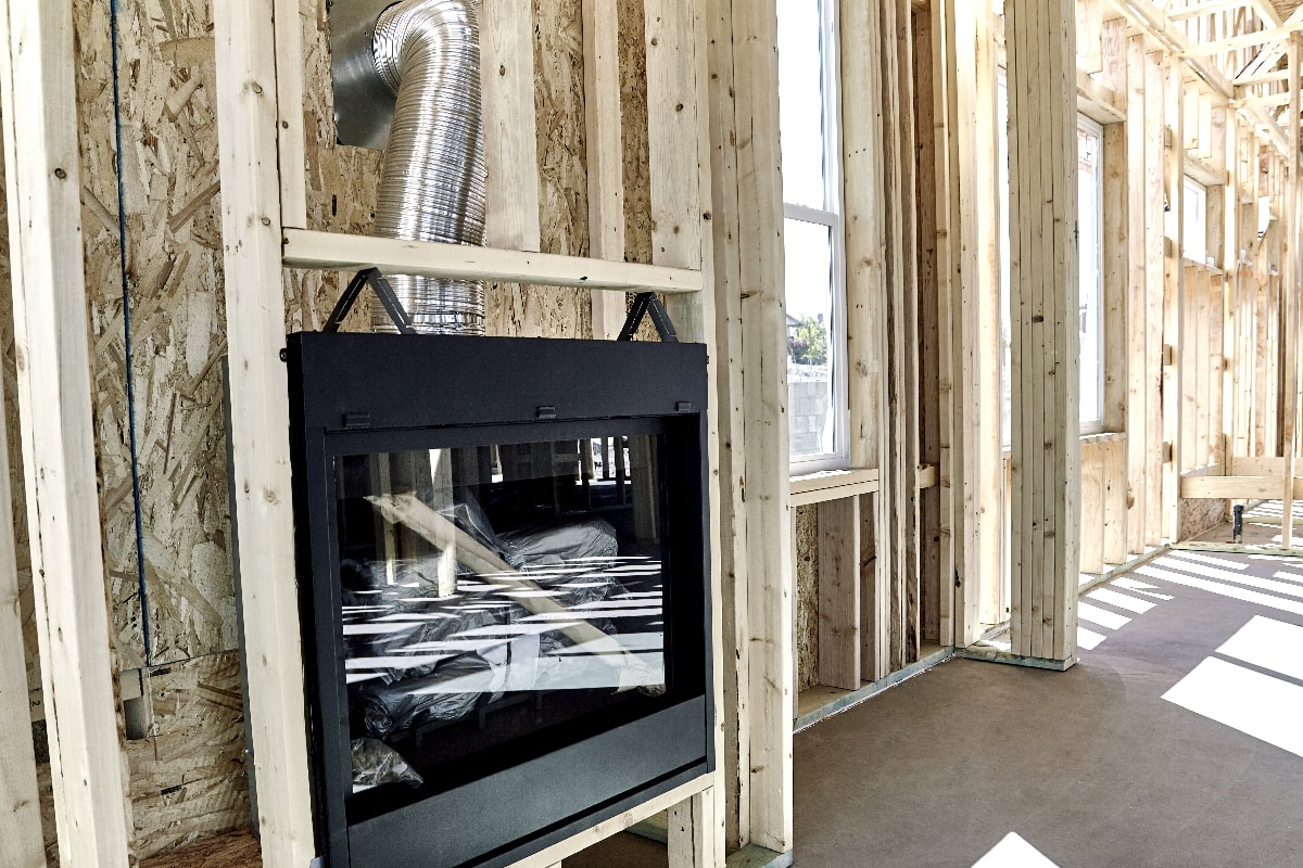 Framed home showing installation of a gas fireplace with vent