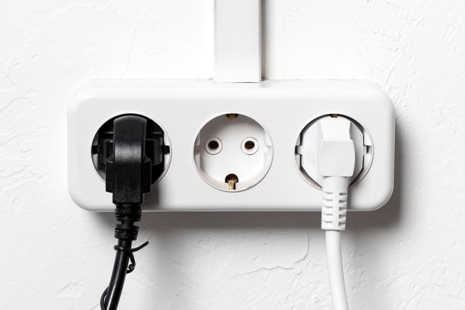 Group of white european electrical outlets with two plugs inserted into it on white concrete wall with banner. Wide panoramic header