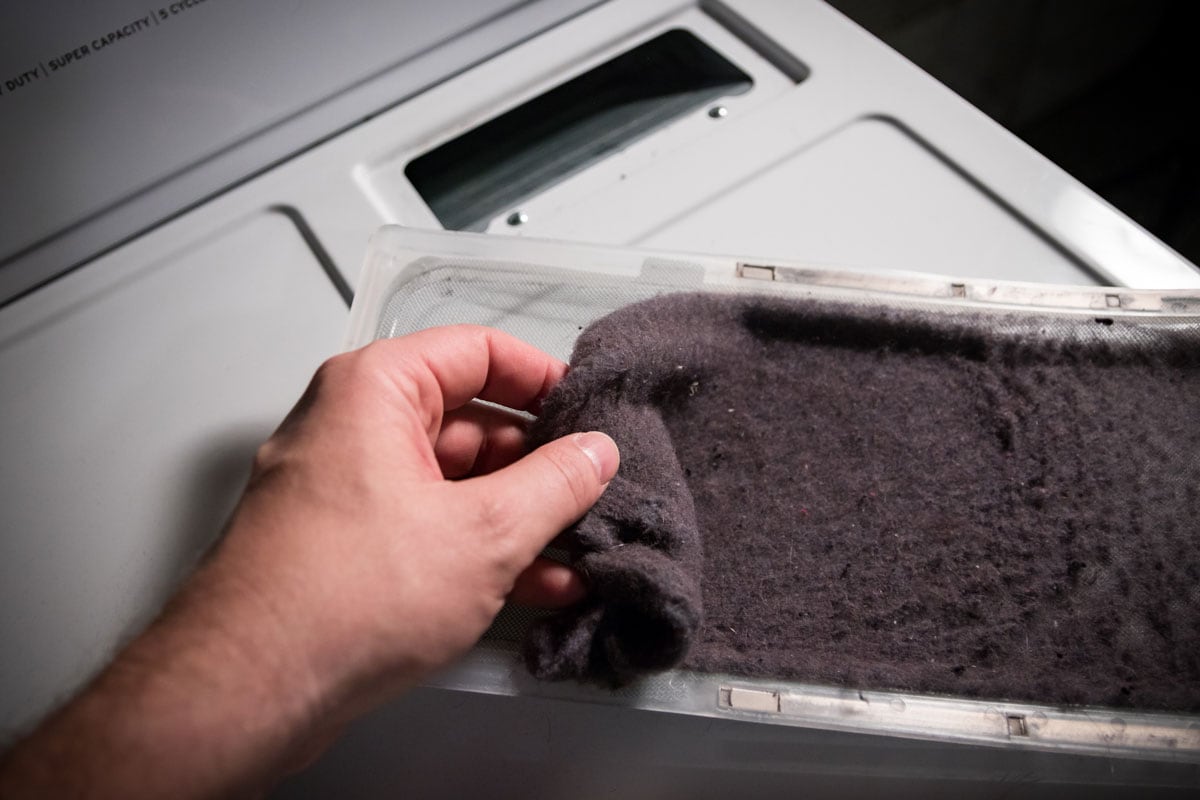Hand cleaning accumulated clothing lint from trap in clothes dryer