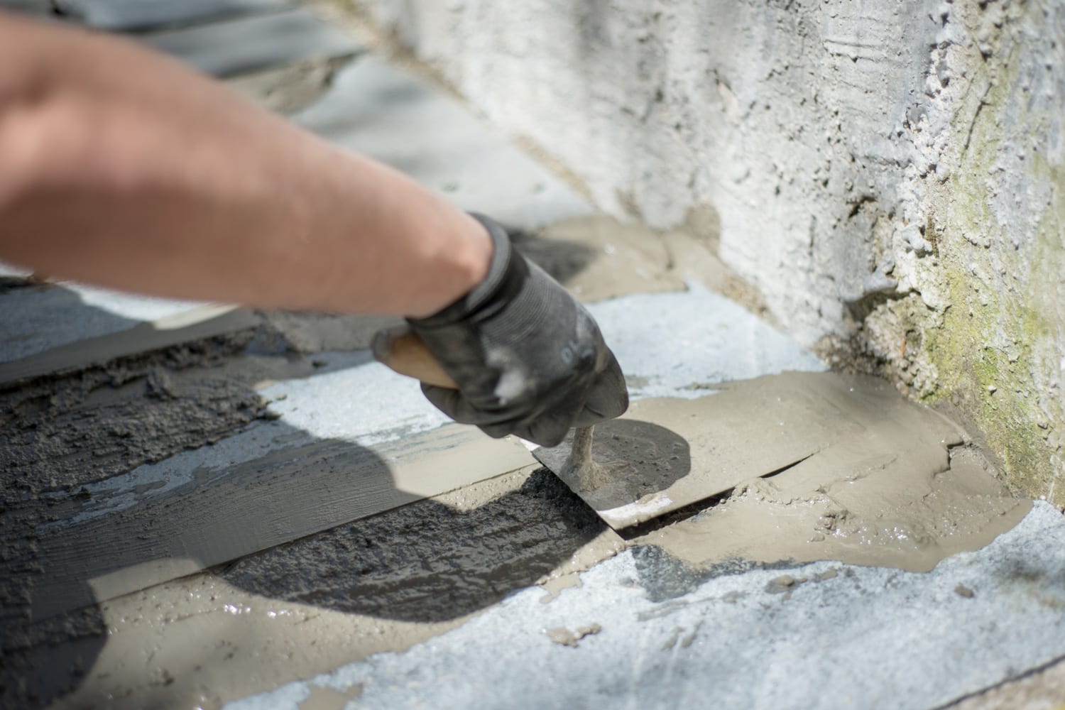 Joint filler in use, male's hand filling cracks with liquid cement on order to repair of cracks in concrete