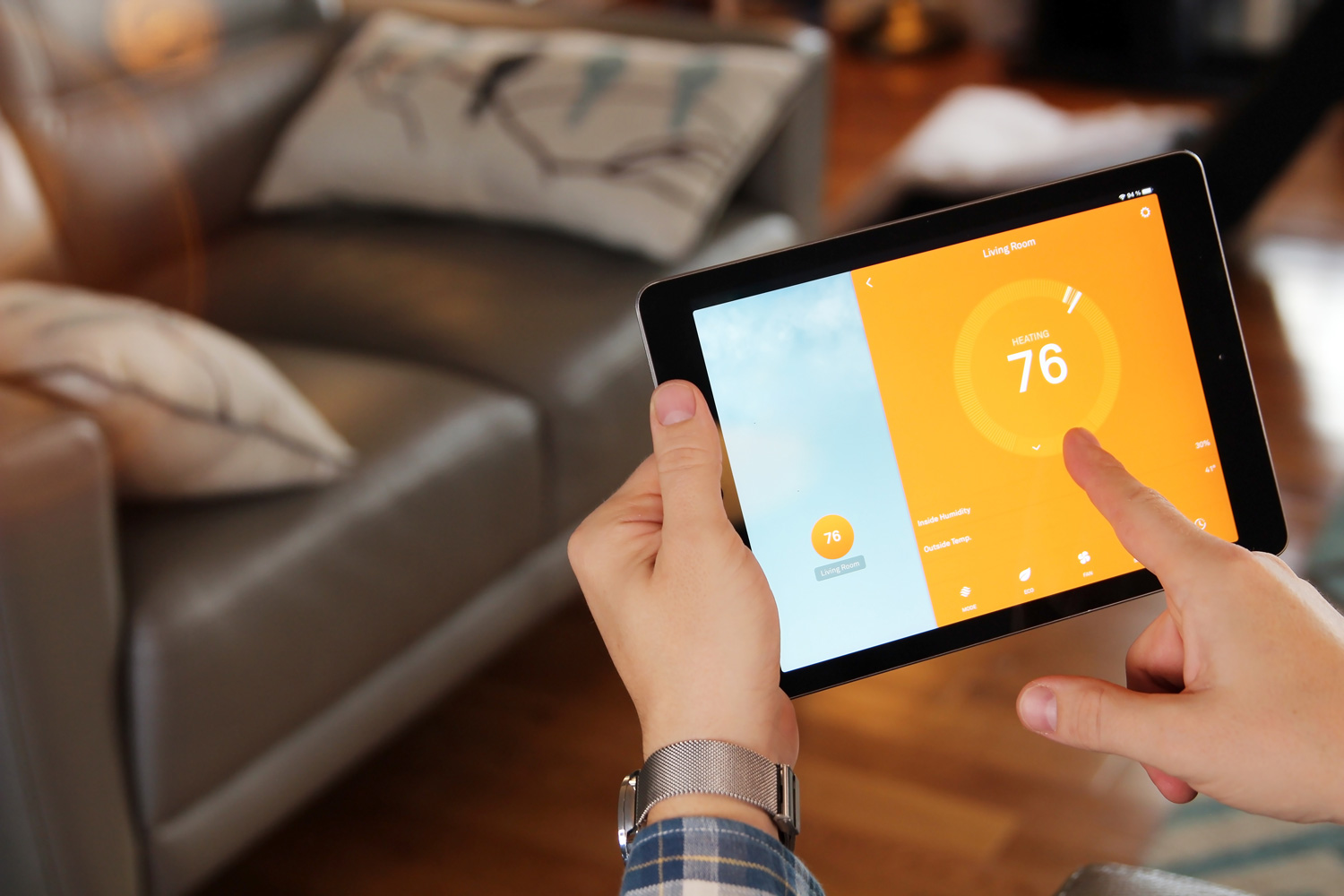 Man is Adjusting a temperature using a tablet with smart home app in modern living room. 