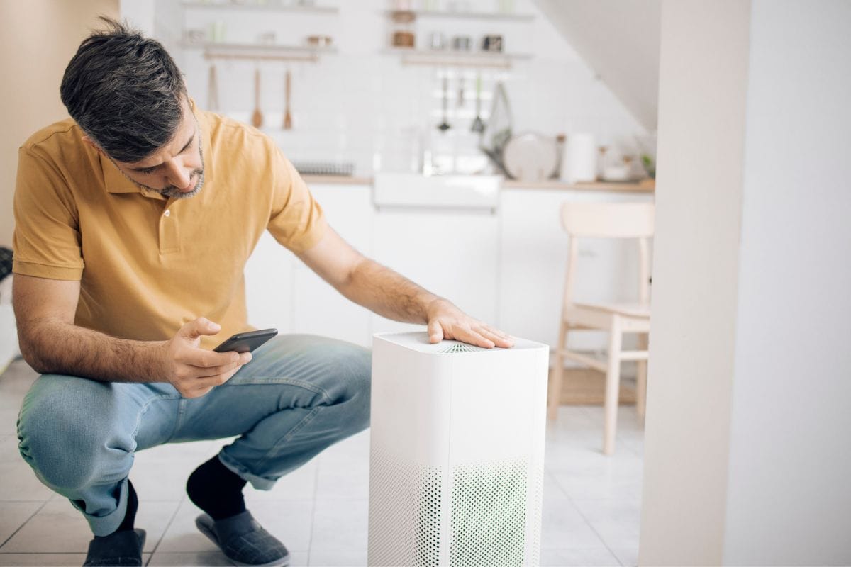 Mid adult man setting up the air purifier using a mobile app.