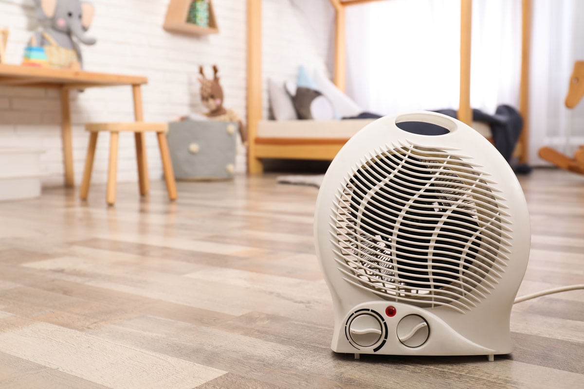 Modern electric fan heater on floor at room