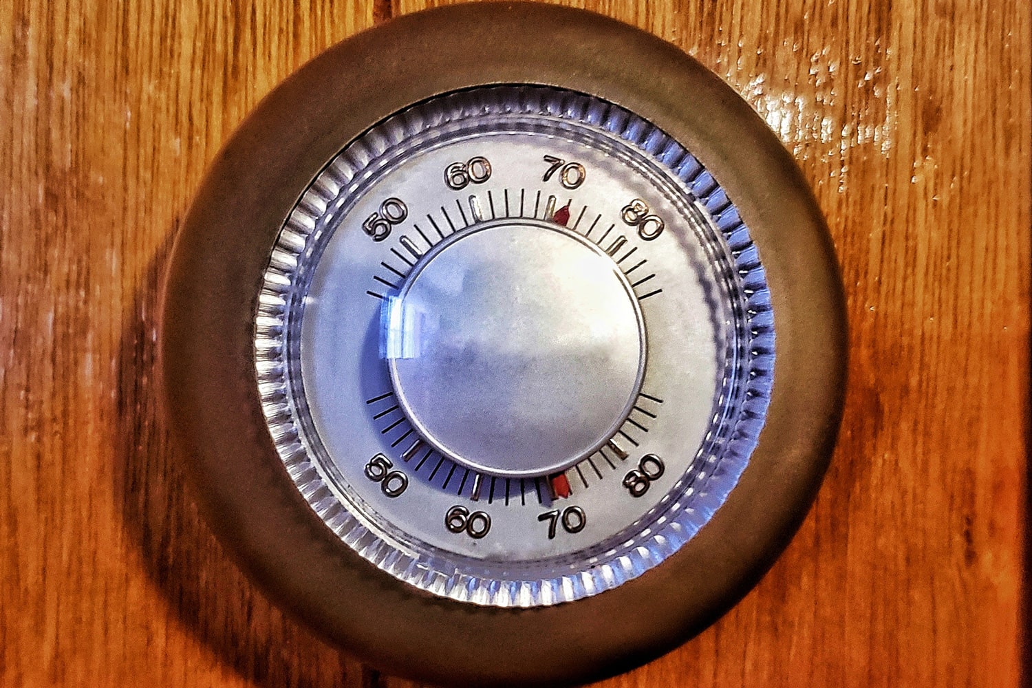 Old brown circle thermostat on brown wooden wall
