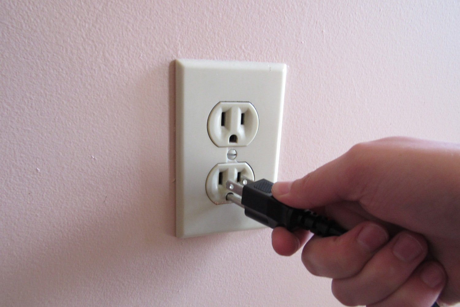 Person putting plug into American wall outlet