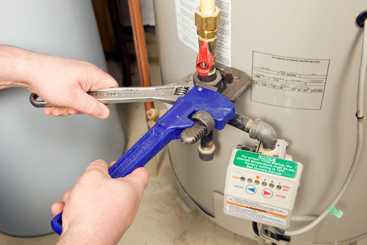 Plumber Pipe and Adjustable Wrenches on Water Heater Gas Line