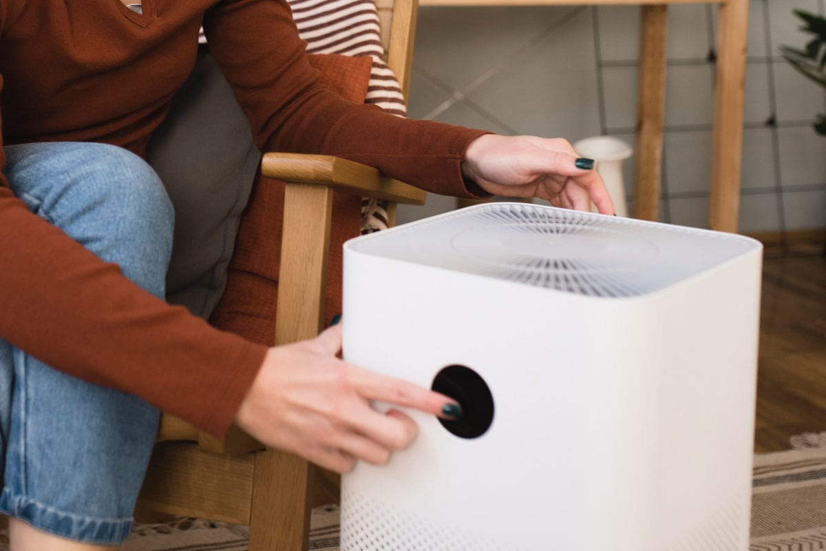 Portrait of a young woman turning on a new air purifier at her house