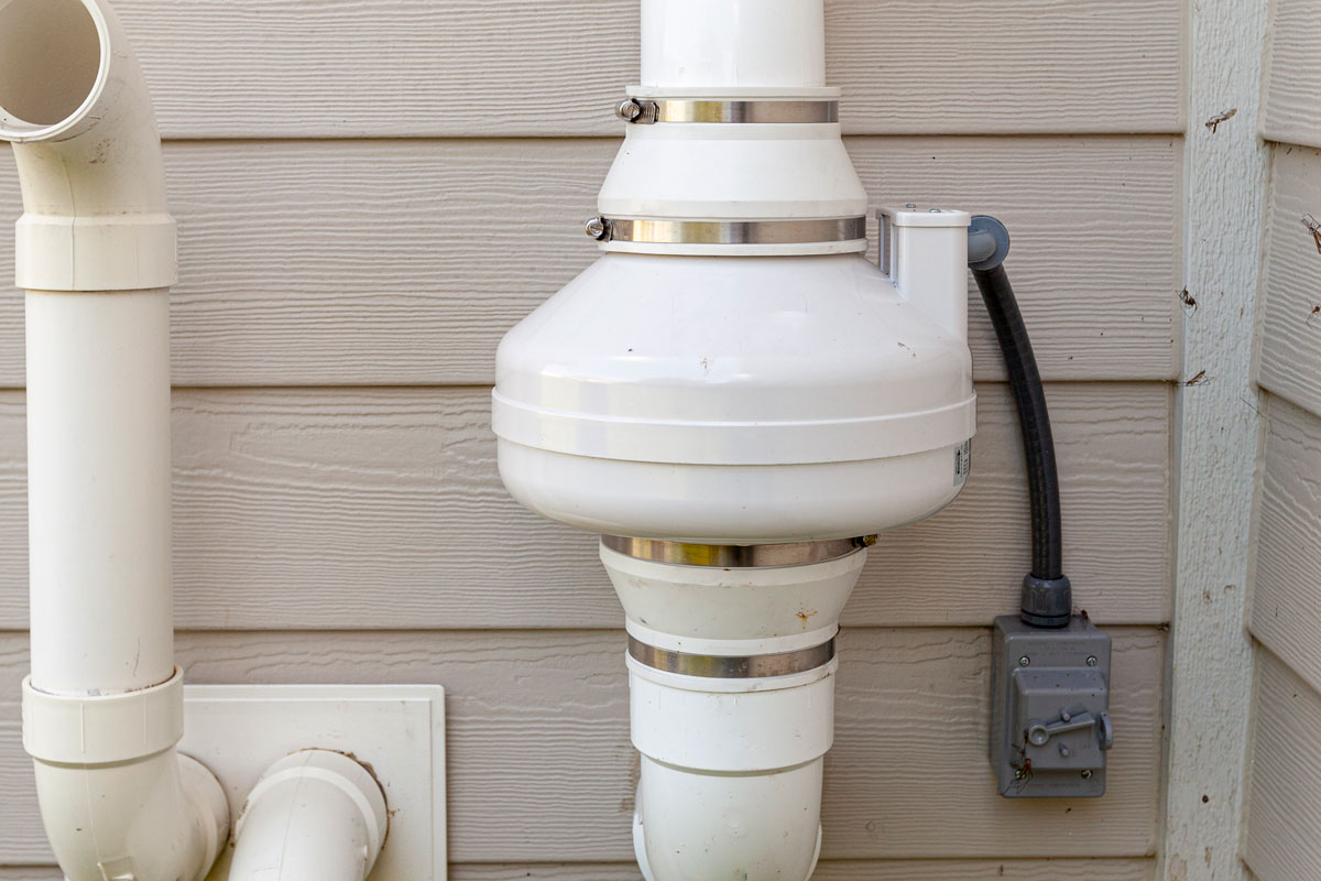 Radon mitigation system engine attached to a house