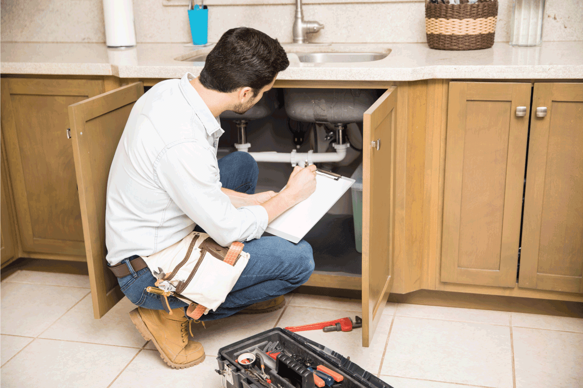 Rear view of a male plumber writing a repair order