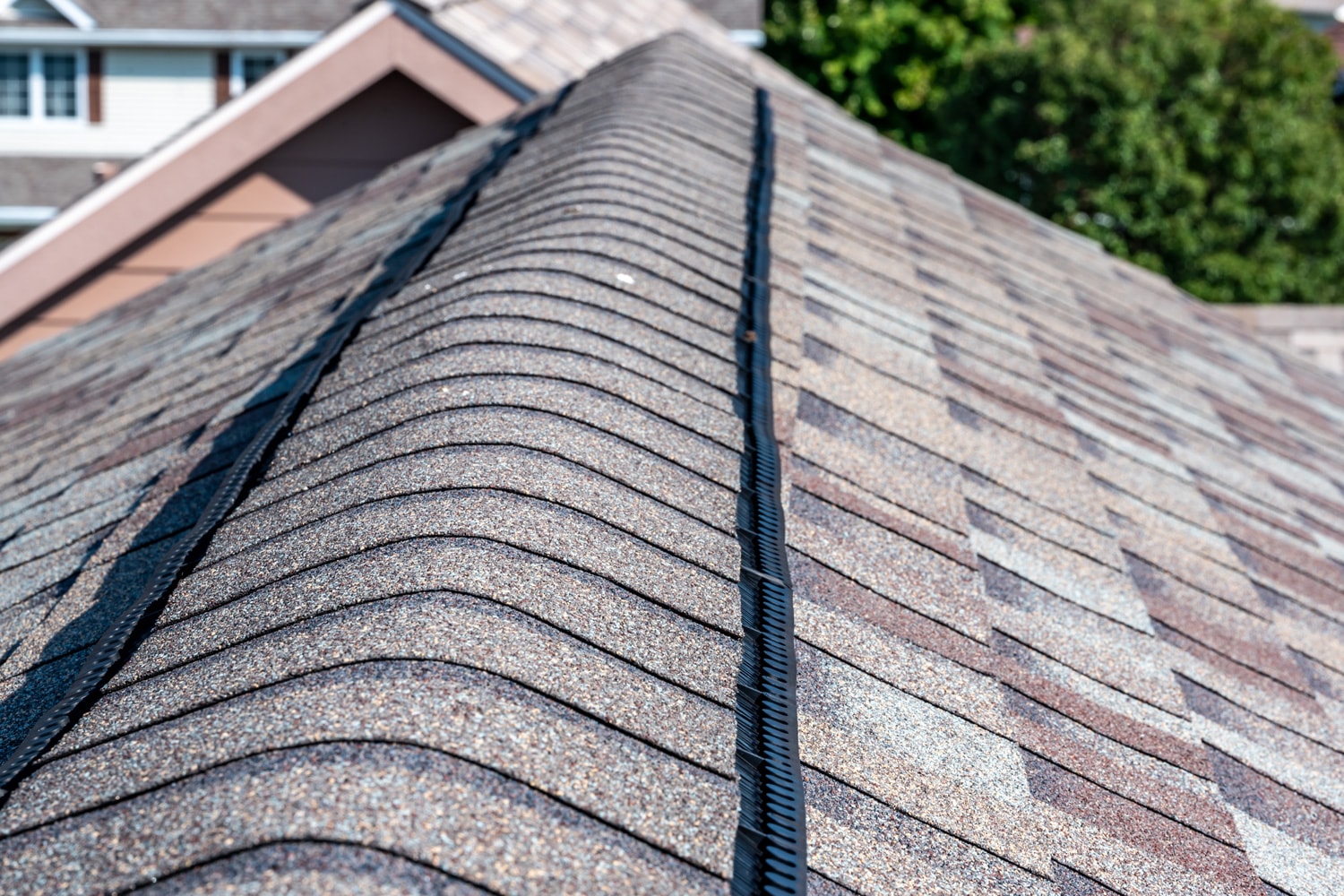 Ridge cap vent installed on a shingle roof for passive attic ventilation on a residential house.