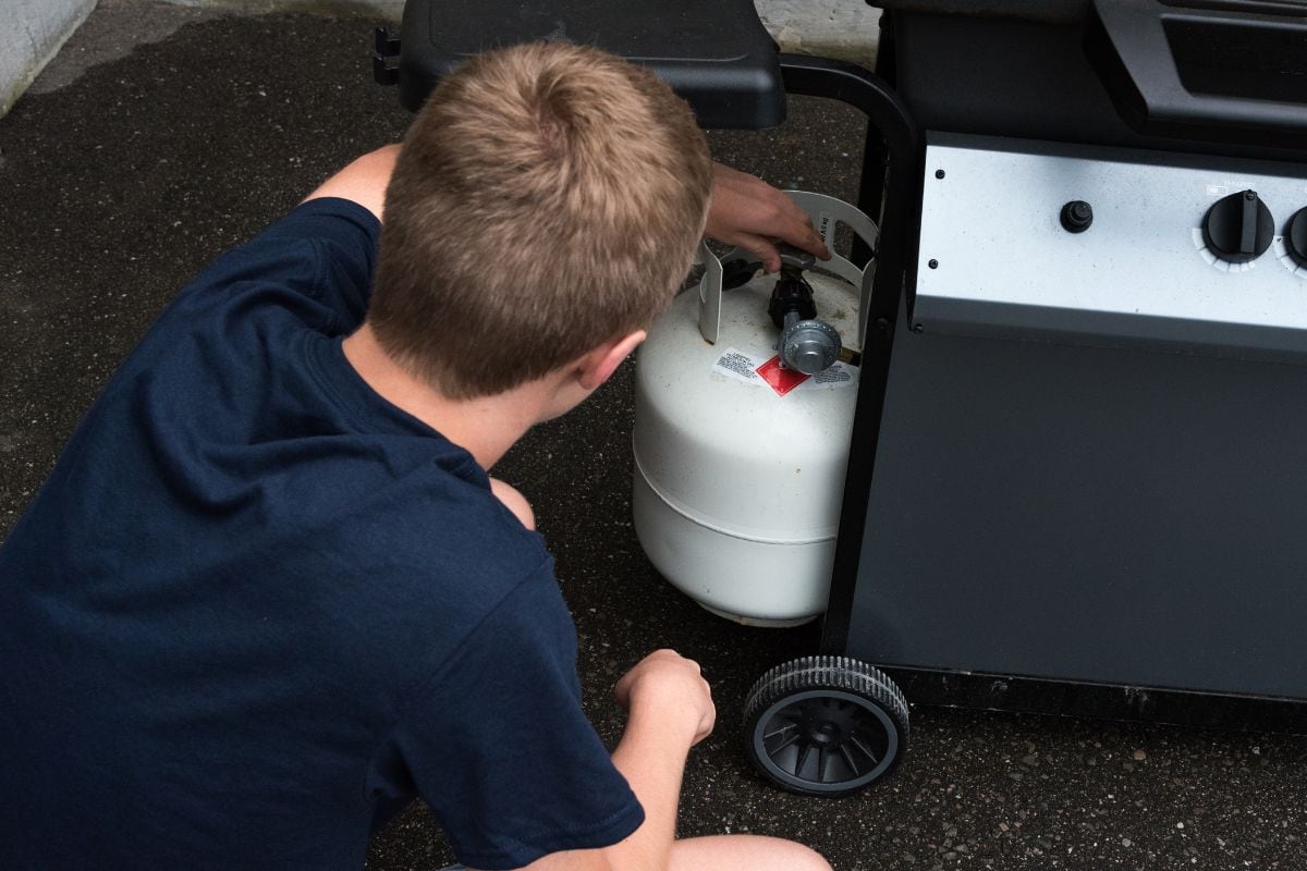 Teenager opening a propane tank for a barbecue, Canada.