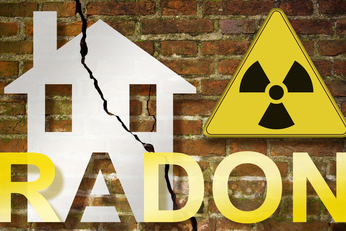 The danger of radon gas in our homes - concept with an outline of a small house with radon text against a damaged cracked brick wall and radiation hazard sign
