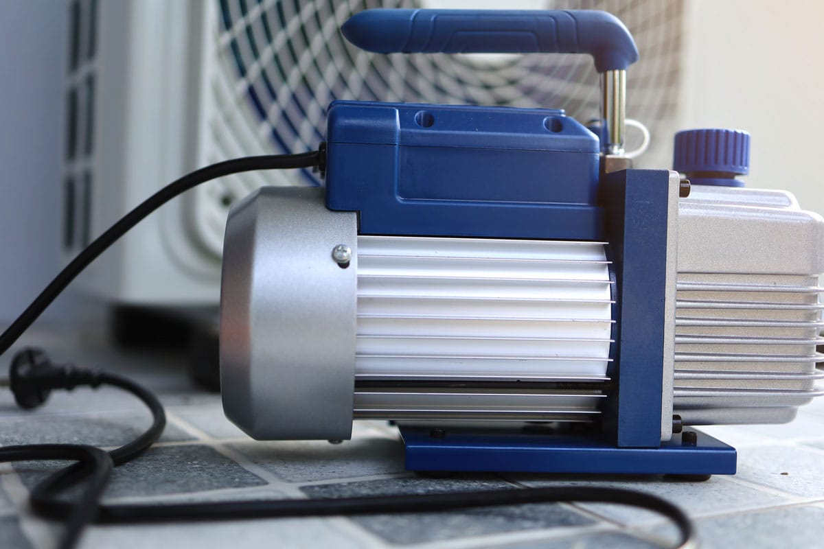 Vacuum pump machine placed infront of the outdoor or condensing unit while air conditioning service in hot summer