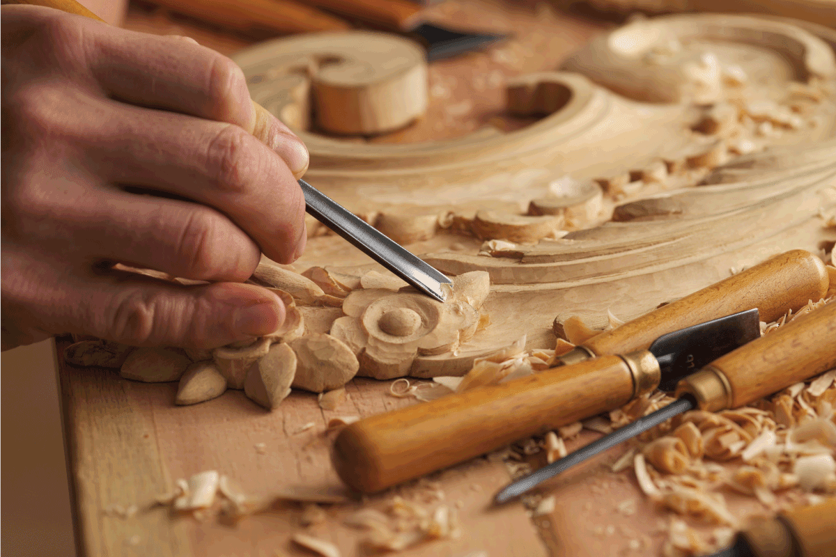 Wood carving. Carpenter's hands use chiesel. Senior wood carving professional during work