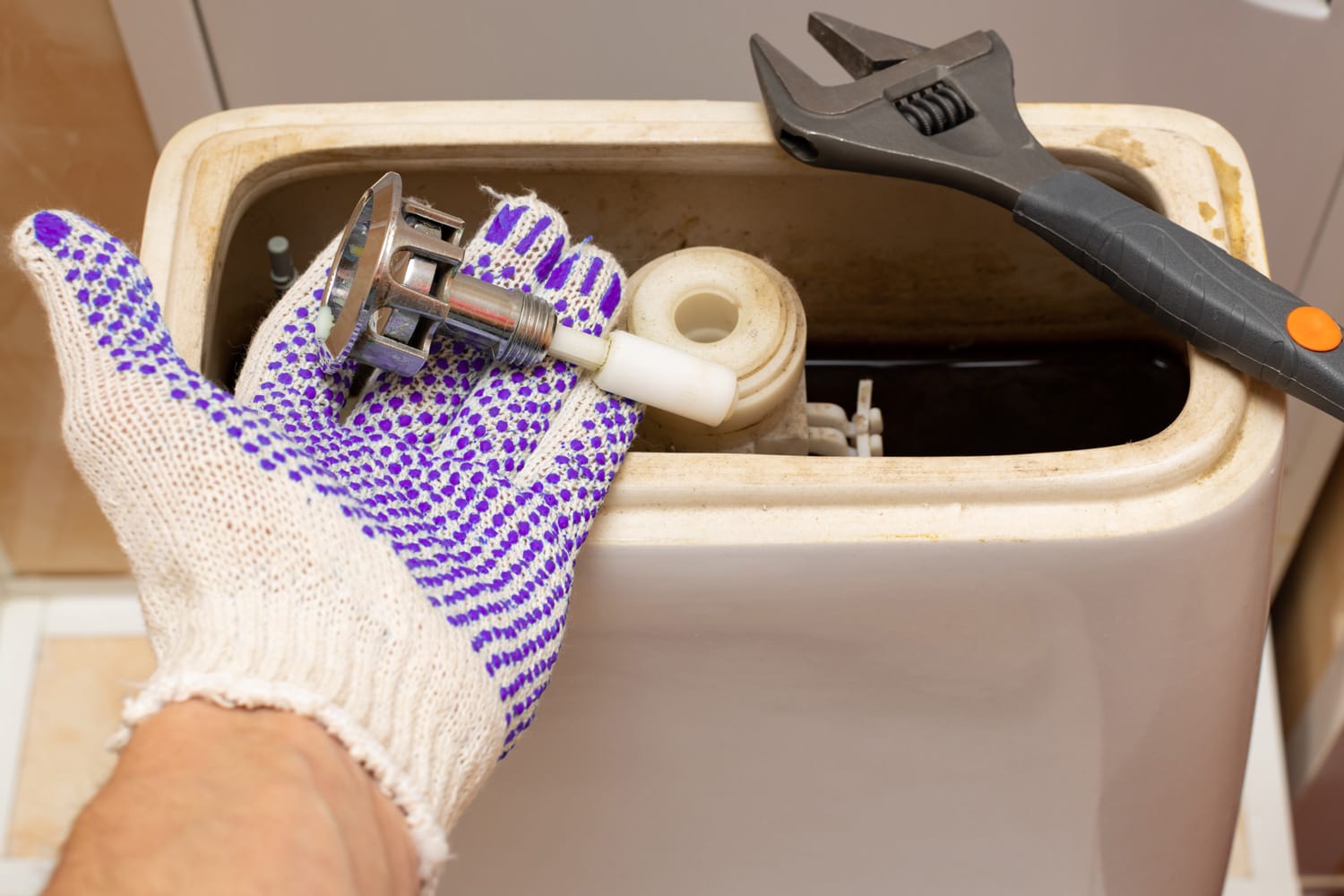hand dismantling the flush mechanism of the toilet tank