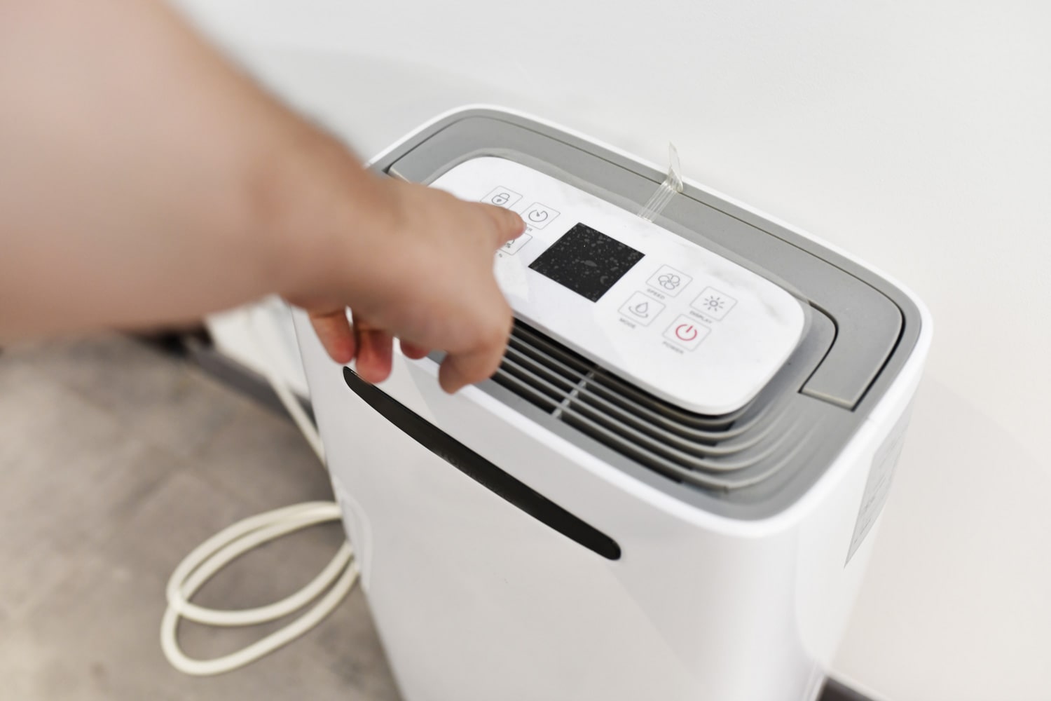 man's hand turning on a dehumidifier in the entrance of a house or office. To prevent joint pain