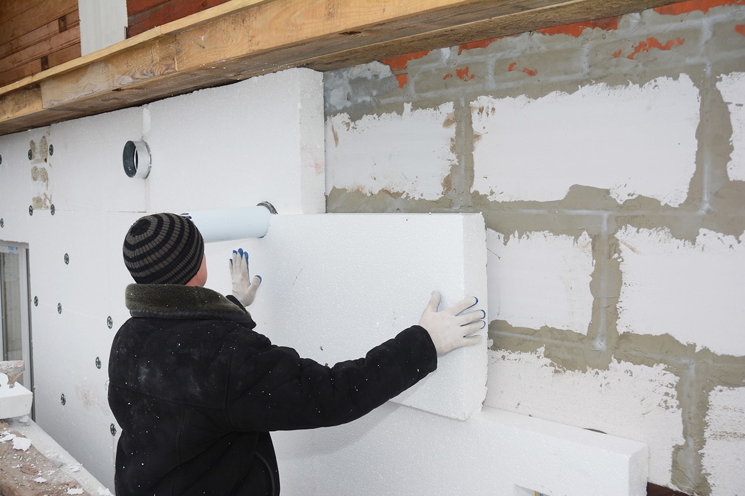 Builder installing rigid styrofoam insulation board for energy saving