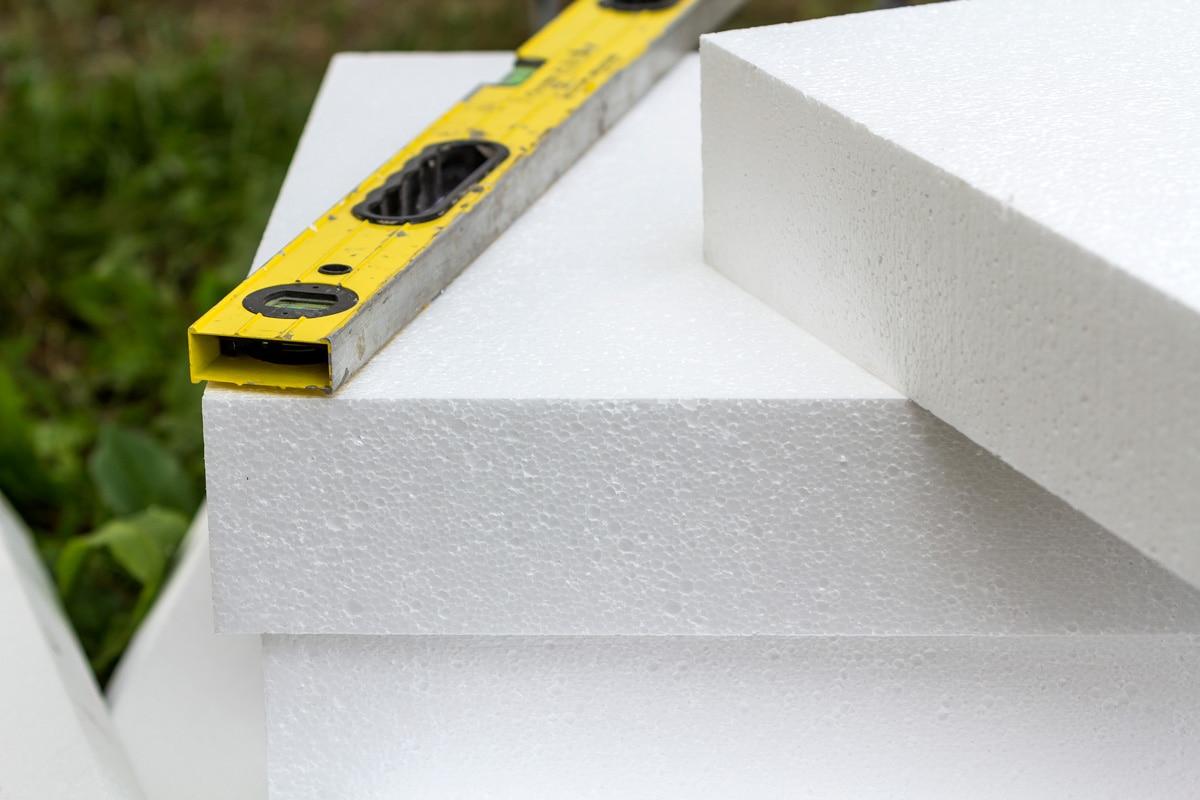 Close-up detail of stack of white rigid polyurethane foam sheets for house insulation and level. 
