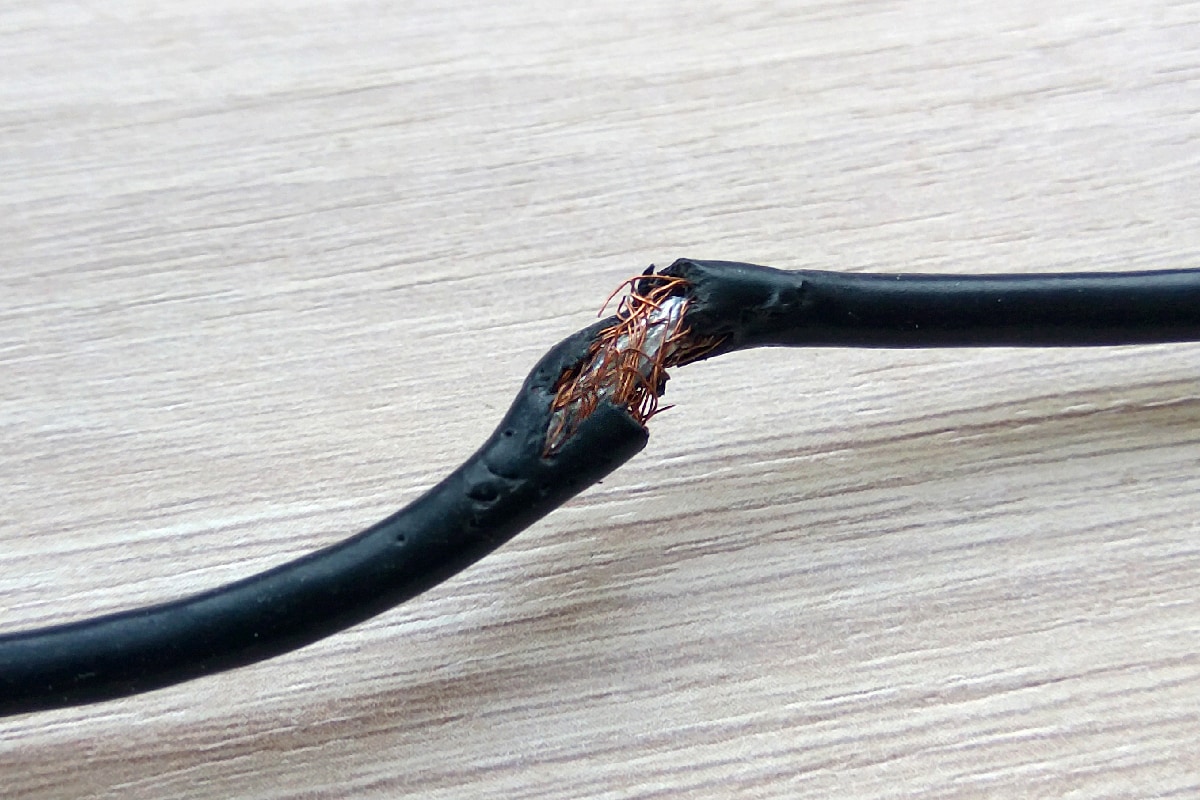 Damaged black electric cord on wooden table