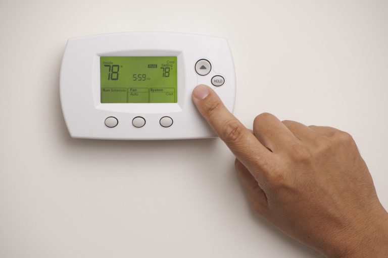 Digital Thermostat with a male hand, set to 78 degrees Fahrenheit. Saved with clipping path for thermostat and hand combined - How To Unlock Pelican Wireless Thermostat [Quickly & Easily]
