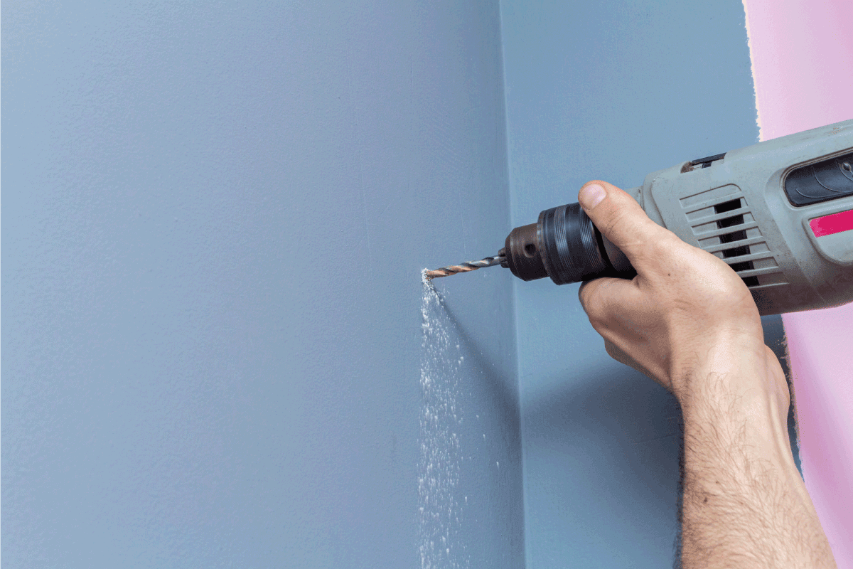 Drilling a gray wall with a power drill. How To Install An Amaze Heater