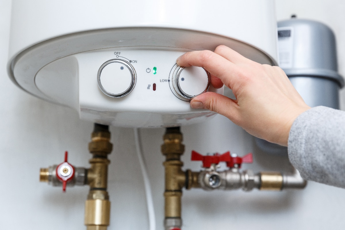 Female hand puts thermostat of electric water heater