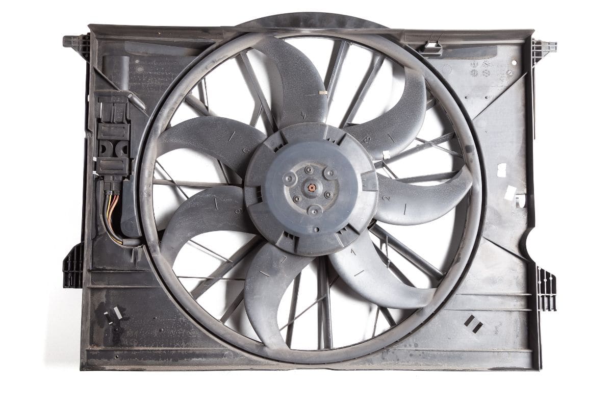 Foreground of metal equipment - engine radiator cooling fan on a white isolated background in a photo studio. Spare part for car repair in a workshop or for sale.