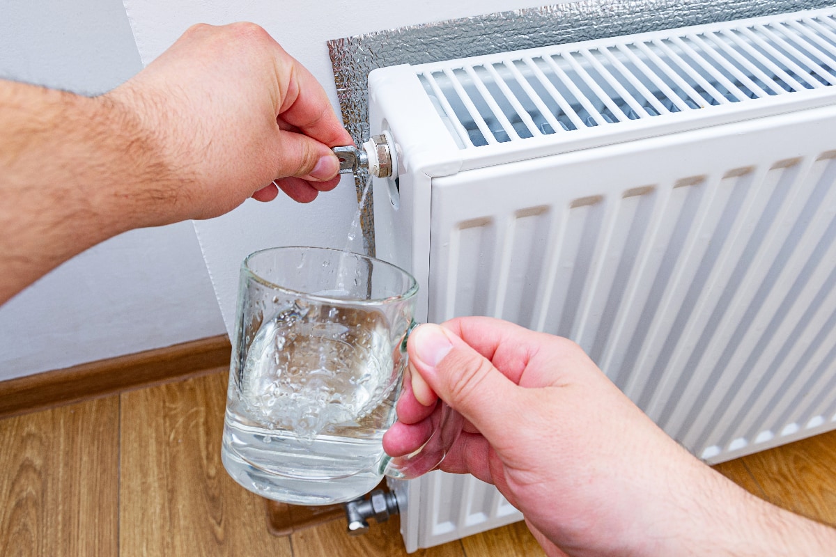 Hand with a key for draining drains water and air from the heater in a cup