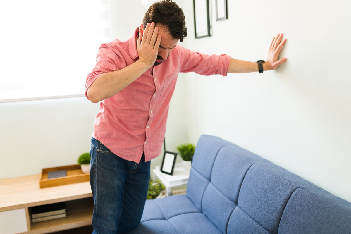 Man feeling dizzy and trying to balance against a wall