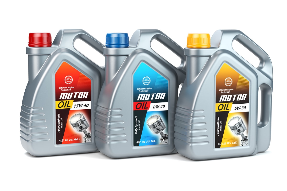 Pllastic motor oil canisters with different types of motor oil on white isolated background.