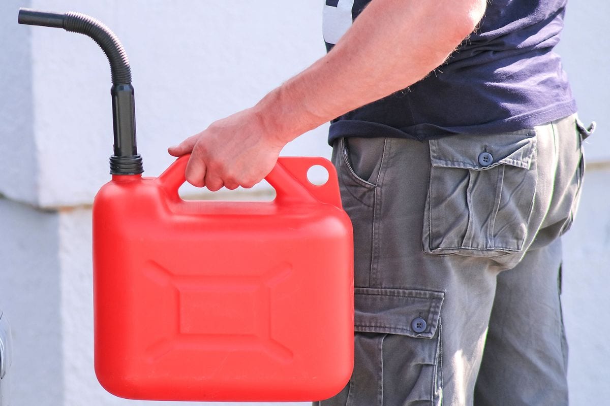 Red canister in the hands of a man. Filling a stalled car with gasoline