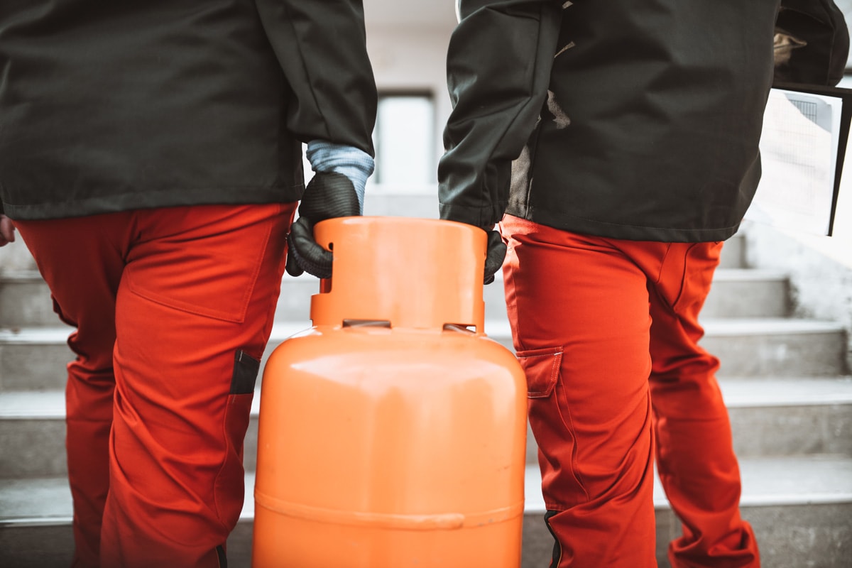 Two workers carrying a propane tank