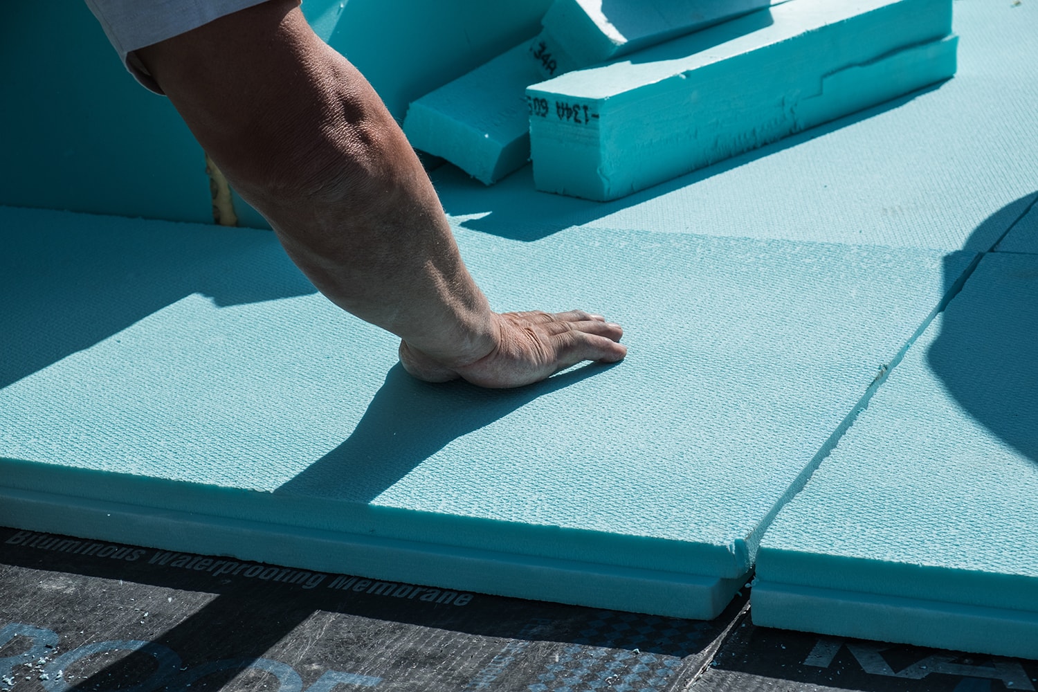 Worker placing XPS polystyrene insulation boards on the flat roof