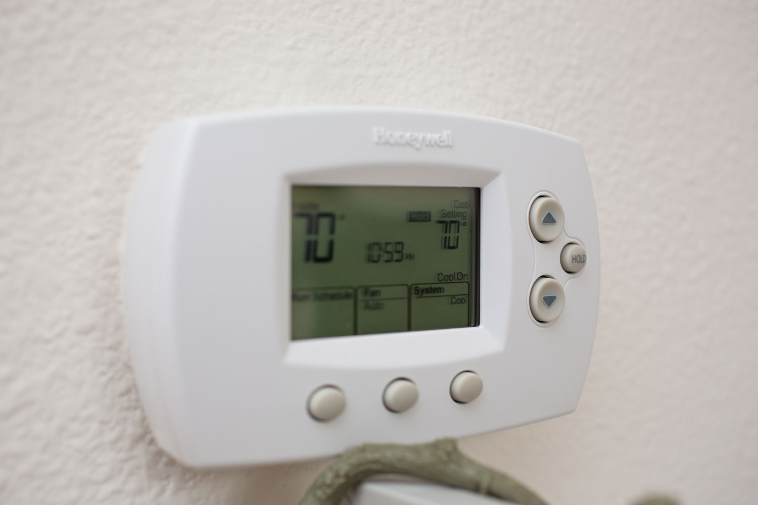 A closeup view of a Honeywell thermostat attached to a wall in a home environment.